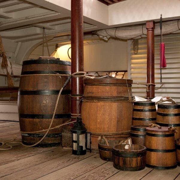 Houten vaten en tonnen met touwen in het ruim van een historisch schip