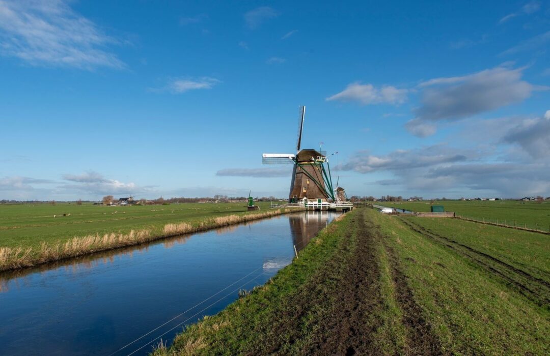 Historisch polderlandschap met windmolen langs een rechte sloot