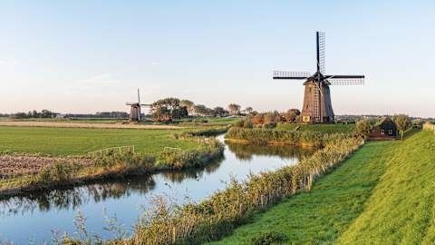 Hollandse polder met molens, sloten en vlakke groene weilanden